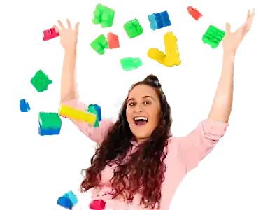 Telissia Gray laughing with her arms raised as colourful toy blocks fly through the air